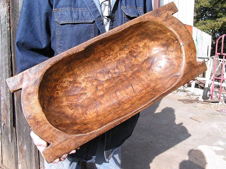 a man holding a large wooden bowl with writing on the bottom and sides in his hands