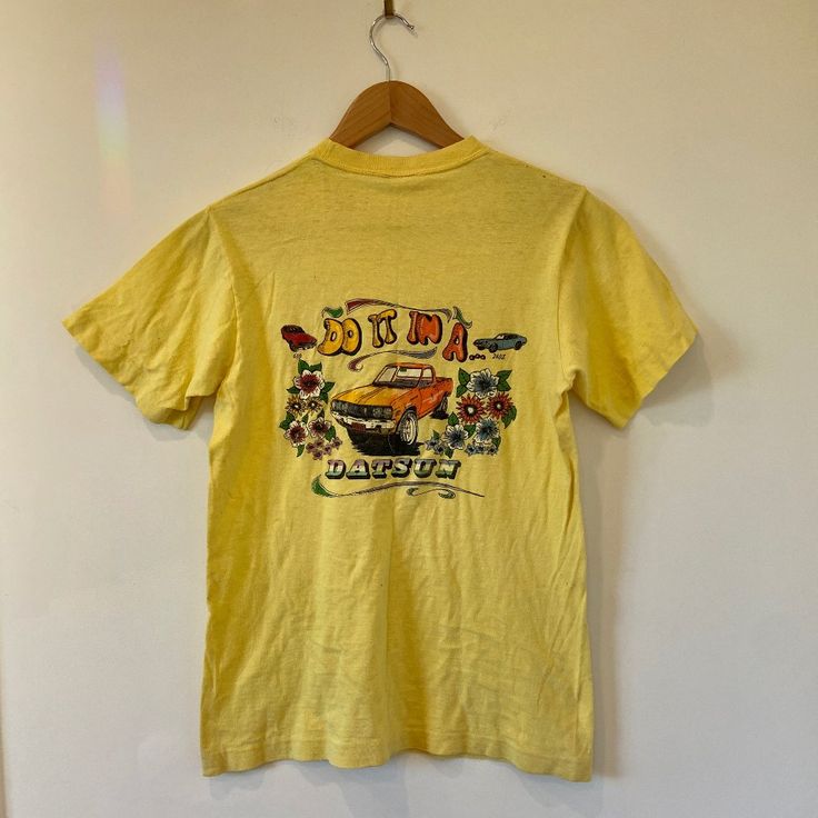 **Rare Design** Vintage1980's Datsun Graphic Tee Sz S. "Do It In A Datsun". Men's/Unisex Size Small. Fabric Is Super Soft And Well Taken Care Of. A Few Small Stains As Seen In Photos. Truly Rare & Hard To Find Online. Dm For Measurements. #Datsun #Vintage #Moto #Car #1980s Retro Yellow Short Sleeve T-shirt, Yellow Retro Short Sleeve T-shirt, Vintage Cropped T-shirt For Summer, Retro Yellow Shirt With Screen Print, Retro Yellow T-shirt With Screen Print, Yellow Retro T-shirt With Graphic Print, Retro Yellow T-shirt With Graphic Print, Retro Yellow Crew Neck Shirt, Yellow Tops With Vintage Print For Summer