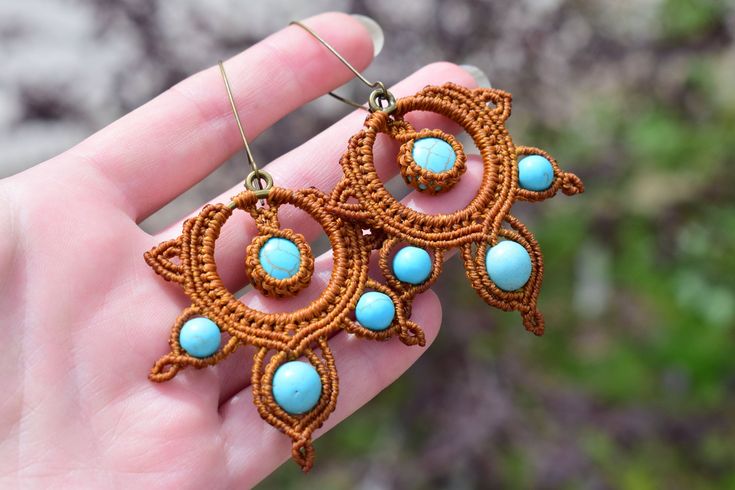 These stunning macrame earrings in warm brown tones are the perfect accessory for any boho lover. Handcrafted with care and attention to detail, these earrings feature a unique round design adorned with beautiful turquoise beads fashioned into delicate petals. The intricate macrame technique adds a beautiful texture and dimension to the piece, making it truly one-of-a-kind. The warm brown color of the macrame cord perfectly complements the bright turquoise beads, creating a harmonious and eye-catching contrast. These earrings are perfect for any occasion, whether you're dressing up for a special event or adding a touch of boho flair to your everyday look. With their lightweight and comfortable design, you'll love wearing them all day long. These macrame earrings would make a wonderful addi Bohemian Brown Earrings As Gift, Bohemian Brown Earrings For Gift, Earthy Brown Earrings For Festivals, Handmade Bohemian Brown Earrings, Handmade Brown Bohemian Earrings, Handmade Brown Earrings For Festival, Earthy Brown Macrame Jewelry, Handmade Brown Earrings For Beach, Handmade Brown Earrings For The Beach