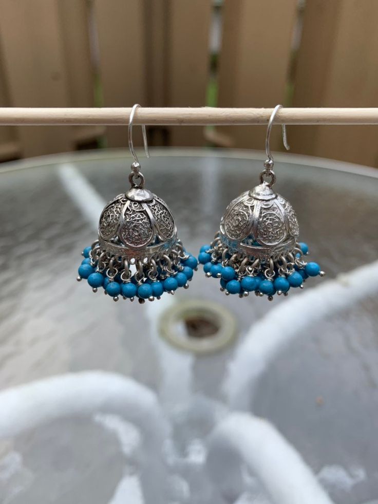 "I have accented a filigree jhumka base liberally with blue beads. These are an adornment to your earlobes. Pair this with any outfit you can dream of, you will not be disappointed.  These are famous in Jaipur, Rajasthan and Lucknow, filigree jhumkas are a rage and works well with any outfit. Total length is 1.5\". Metal - Sterling Silver. Please feel free to ask me for more pictures or questions. Thank You for Shopping Jhumkas they are Ancient, Elegant, Opulent and Regal!" Traditional Handmade Blue Danglers, Blue Bohemian Jhumkas For Festive Occasions, Festive Blue Tilla Jhumkas, Festive Blue Bohemian Jhumkas, Festive Bohemian Blue Jhumkas, Bohemian Blue Danglers For Wedding, Blue Bohemian Danglers For Wedding, Blue Festival Earrings With Latkans, Bohemian Beaded Danglers For Festive Occasions