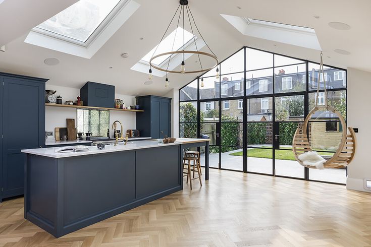 an open kitchen and dining area with skylights in the ceiling, wooden flooring and blue cabinets