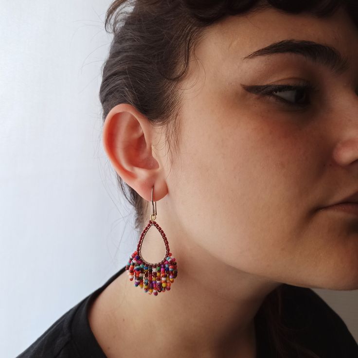 These earrings are composed of burgundy and multicolored (burgundy, red, orange, yellow, purple, turquoise...) seed beads that are sewn around a teardrop steel base by means of silk thread. Steel hook with silicone stoppers. Red Teardrop Earrings With Dangling Beads, Red Teardrop Jewelry With Tiny Beads, Handmade Multicolor Teardrop Earrings For Parties, Red Teardrop Beaded Earrings With Dangling Beads, Multicolor Teardrop Beaded Earrings, Red Teardrop Beaded Dangling Earrings, Purple Teardrop Beaded Earrings, Red Teardrop Earrings With Tiny Beads, Multicolor Beaded Teardrop Earrings