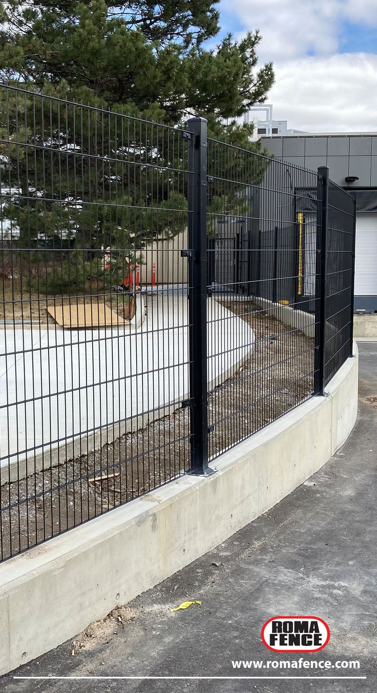 a fenced in parking lot with trees behind it