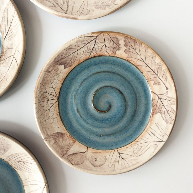 four ceramic plates with designs on them sitting on a white table top next to each other