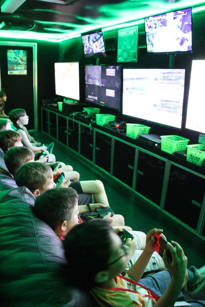 people are playing video games on the big screen tvs in this room with green lighting