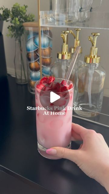 someone is holding up a pink drink with strawberries in it