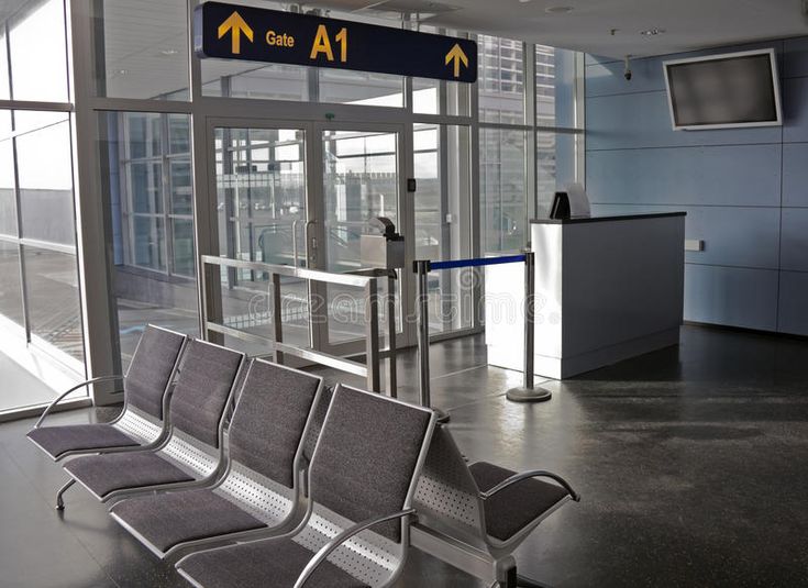 an airport waiting area with chairs and signs