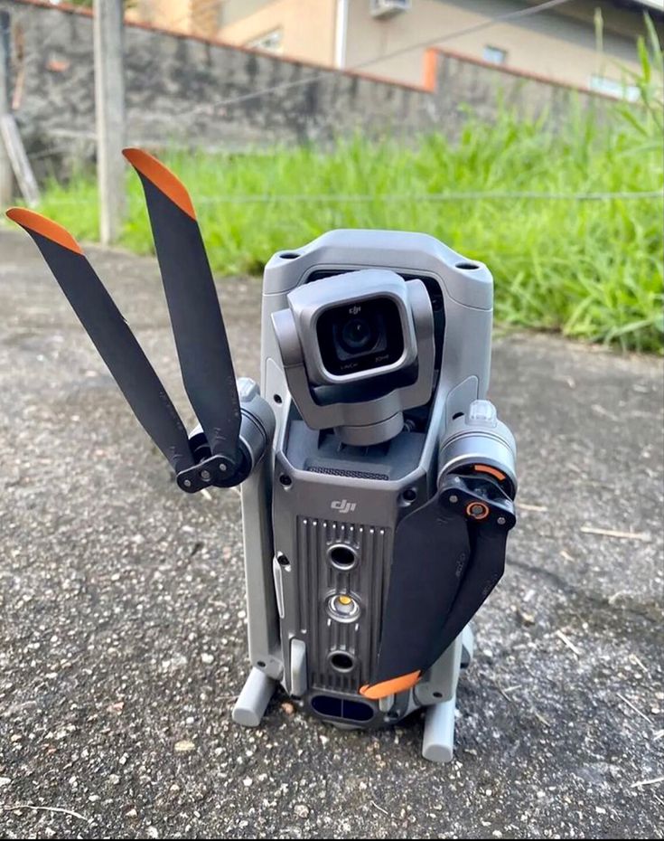 a small camera with two propellers attached to it's body and sitting on the ground