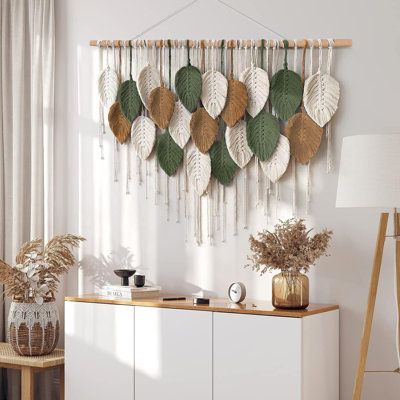 a room with white furniture and lots of green leaves hanging on the wall above it