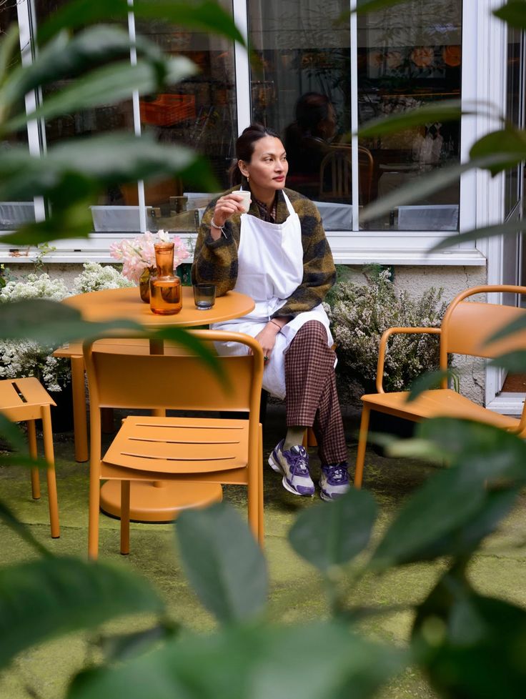 a woman sitting at an orange table outside