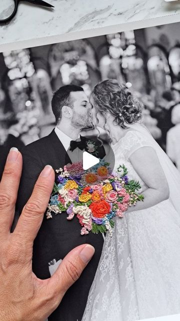 a man and woman kissing in front of a wedding photo with flowers on the heart