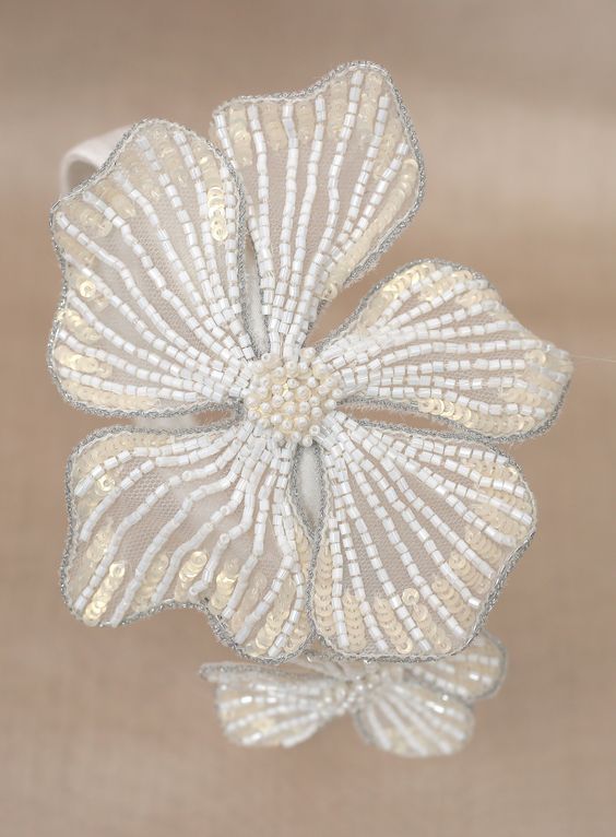 a white flower with beading on it sitting on top of a cloth covered surface