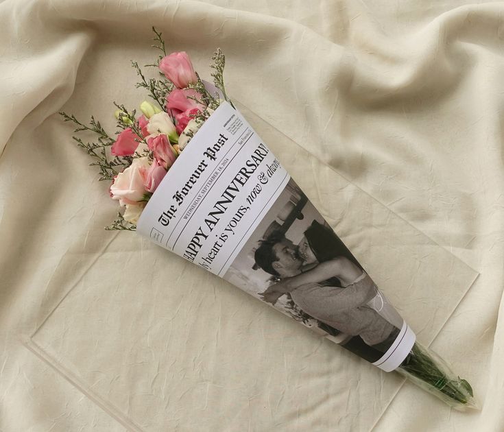 a bouquet of flowers laying on top of a white sheet next to a magazine cover