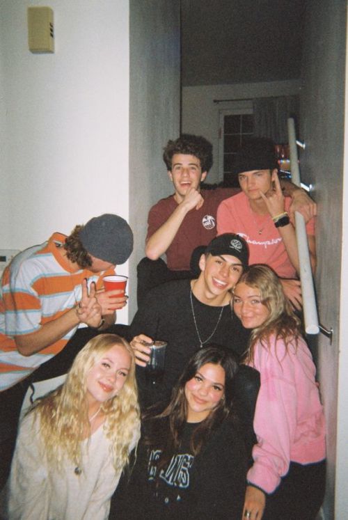 a group of young people standing next to each other holding baseball bats and drinking coffee