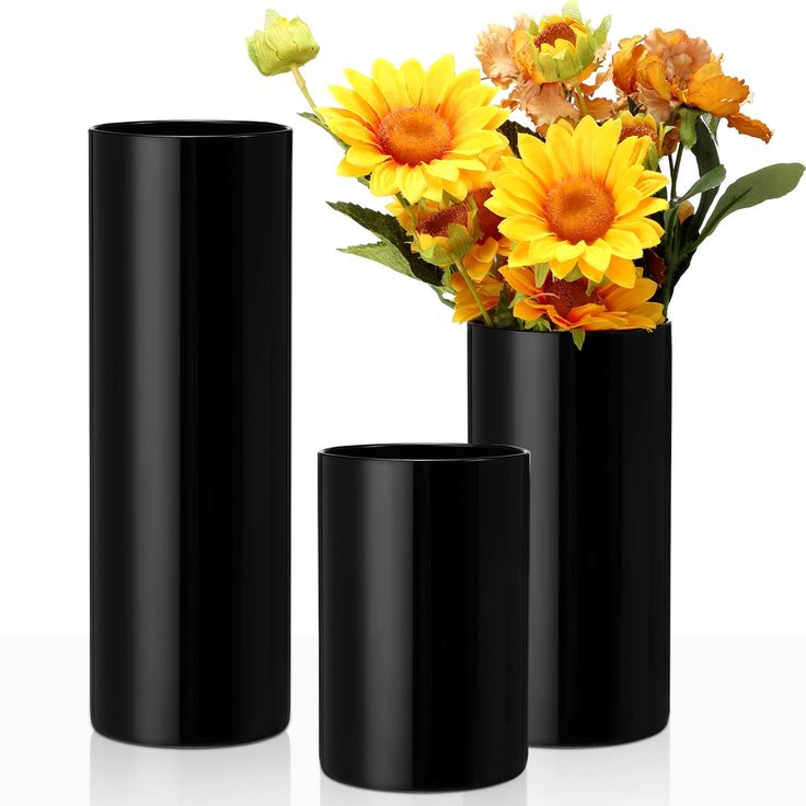 three black vases with yellow flowers in them