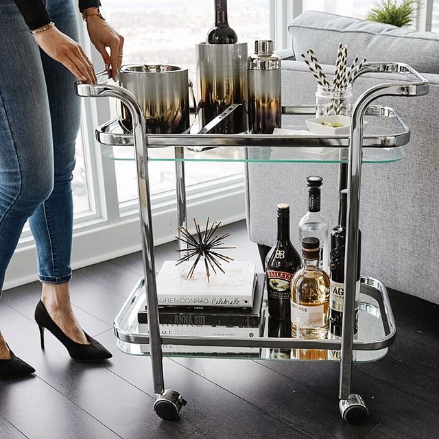 a woman standing next to a table with bottles and glasses on it