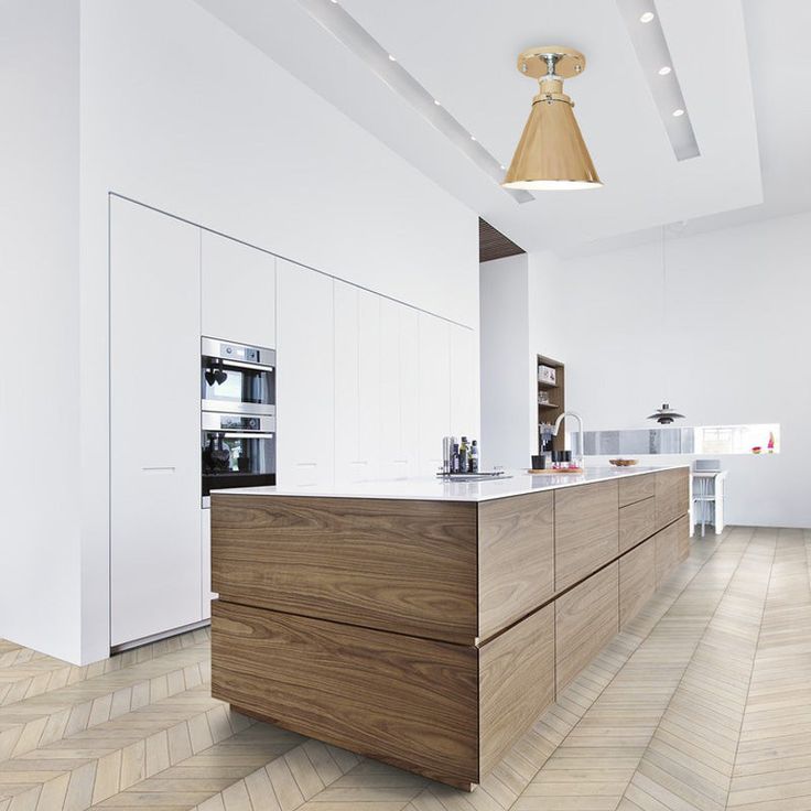 a modern kitchen with white walls and wood flooring, an island in the middle