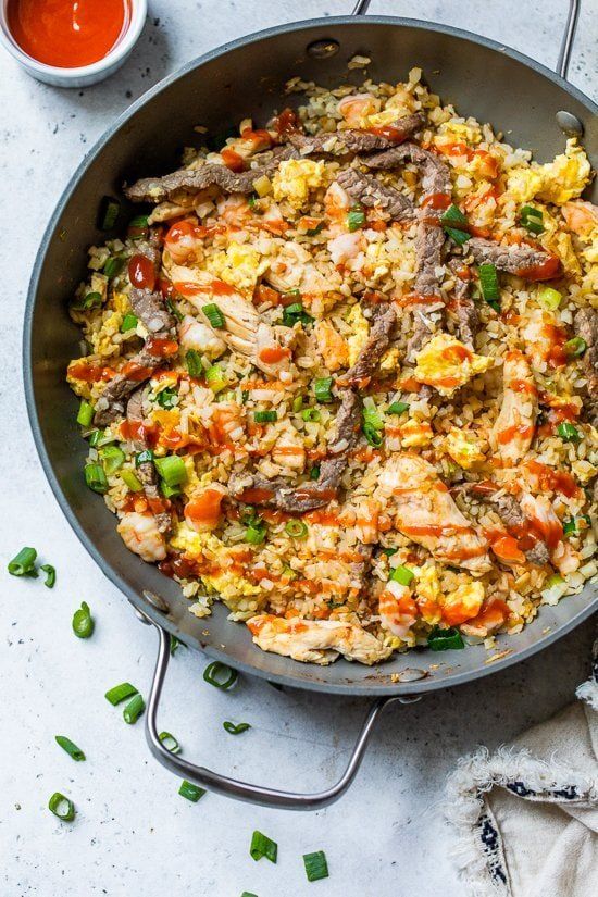 a skillet filled with rice and vegetables next to some sauces on the side