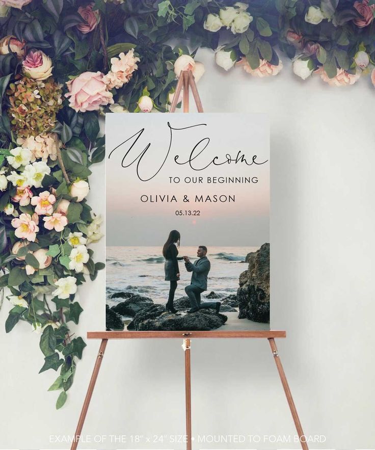 a welcome sign on an easel with flowers in the background