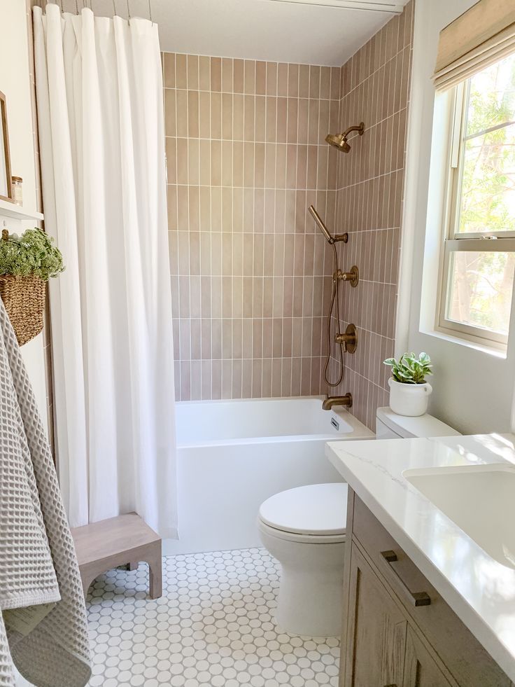 a white toilet sitting next to a bath tub in a bathroom under a window with curtains