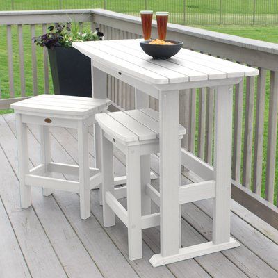 an outdoor table and stools on a deck