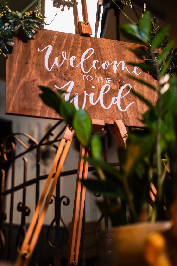 a wooden sign with the words welcome to the bride on it next to some plants