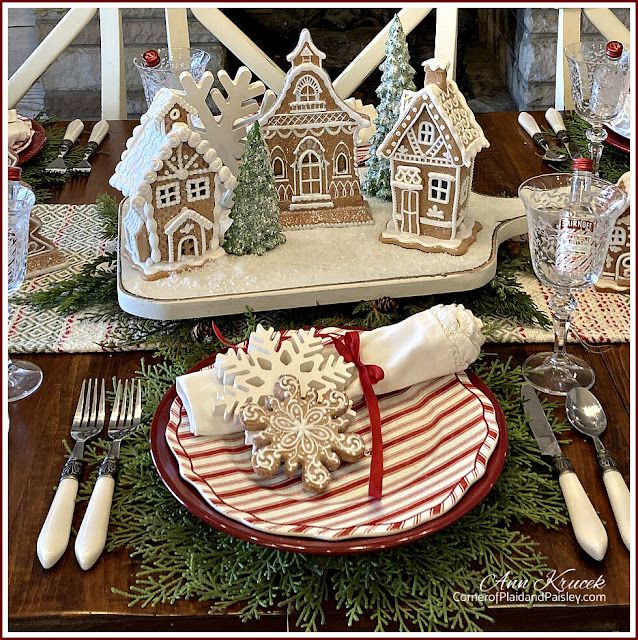 a christmas table setting with gingerbread houses and snowflakes