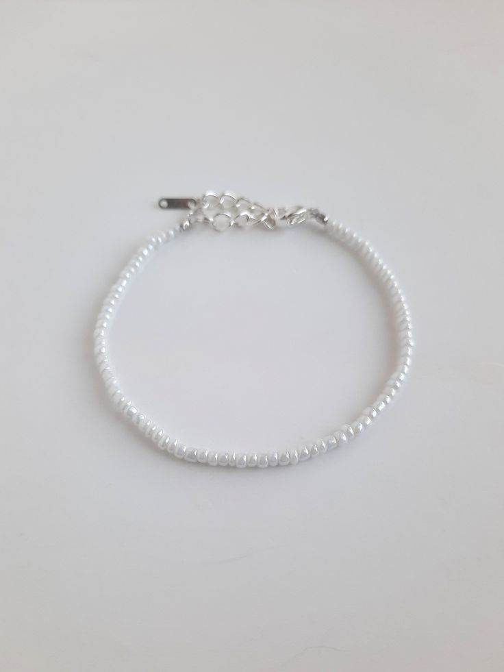 Pearly white seed bead bracelet with silver hardware 4 inch daisy chain with 1 inch extension: 5 inches total 5 inch daisy chain with 1 inch extension: 6 inches total 6 inch daisy chain with 1 inch extension: 7 inches total 7 inch daisy chain with 1 inch extension: 8 inches total Sterling Silver plated lobster clasp and extender Please message me if you would like a different size! White Beaded Chain Bracelets, Everyday White Jewelry With Silver Beads, Minimalist White Beaded Bracelet, Silver Beaded Minimalist Pearl Bracelet, White Beaded Chain Pearl Bracelet Gift, White Dainty Adjustable Beaded Bracelets, Dainty White Adjustable Beaded Bracelets, Adjustable White Pearl Bracelets, Adjustable White Dainty Beaded Bracelets