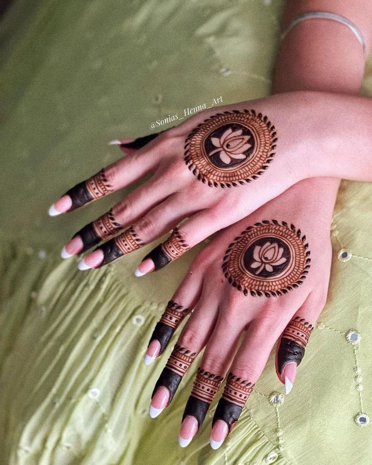 two women with henna tattoos on their hands, one is wearing a green dress