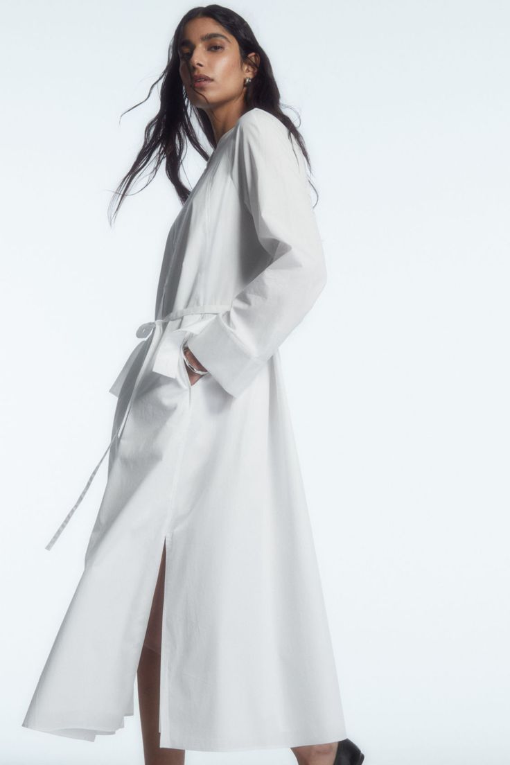 This season, the COS womenswear team reimagine the perennial shirt dress. Crafted from lightweight cotton poplin, it's cut to hit at the ankle and designed with a collarless neckline and an overlapping storm flap detail at the back that borrows from classic trench coats. It's detailed with an elasticated gathered back panel and tonal belt that allows you to personalise the shape. Relaxed fitButton closureSide slits Shell: 100% Cotton (excluding trims) / Machine wash Back length of size EU 36 is 122.3cm / Model wears a size EU 36 Long Shirt Dress For Spring Workwear, Maxi Length Shirt Dress For Summer Workwear, Maxi Length Belted Shirt Dress For Work, Spring Workwear Belted Maxi Dress, Belted Maxi Shirt Dress For Work, Summer Maxi Length Shirt Dress For Workwear, Summer Maxi Shirt Dress For Work, Oversized Midi Dress For Daywear, Chic Dresses With Unlined Sleeves For Daywear