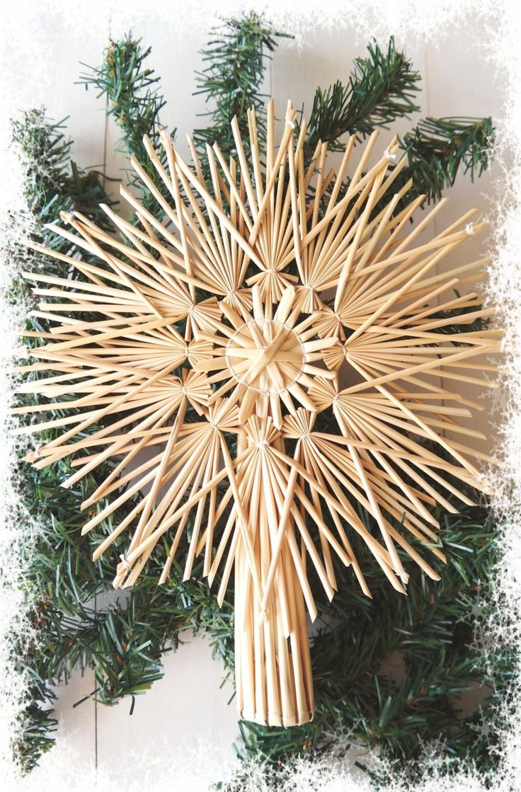 a cross made out of bamboo sticks on top of a tree branch with snowflakes around it