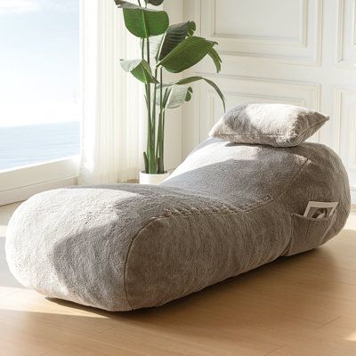 a large bean bag chair sitting on top of a wooden floor next to a plant