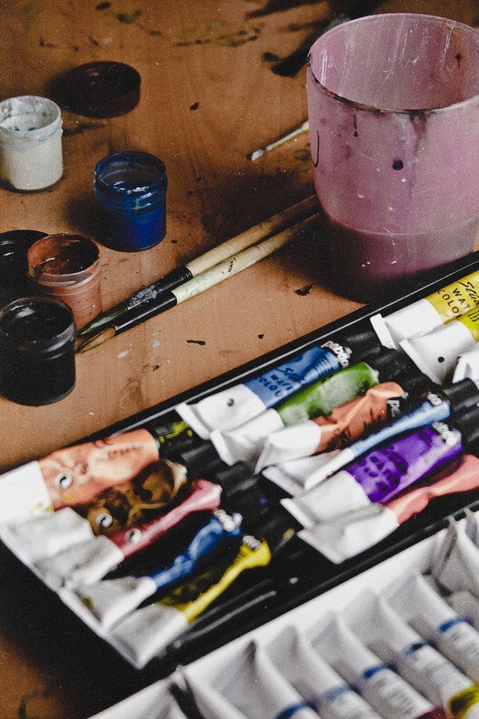 an artist's palette with paint, brushes and other art supplies on a table