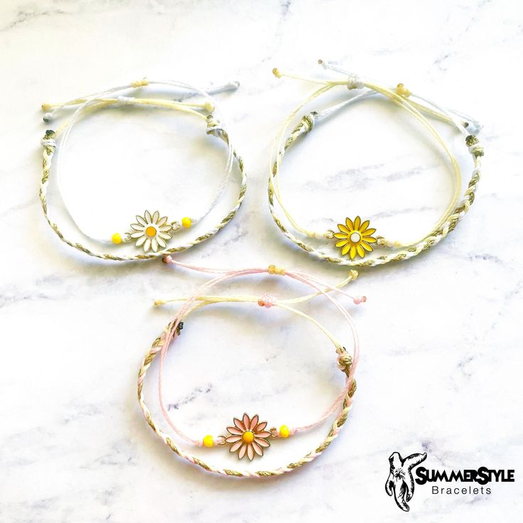 three bracelets with flowers on them sitting on a marble counter top next to each other