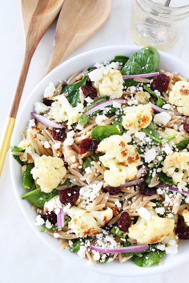 a salad with cauliflower, spinach and feta cheese in a white bowl