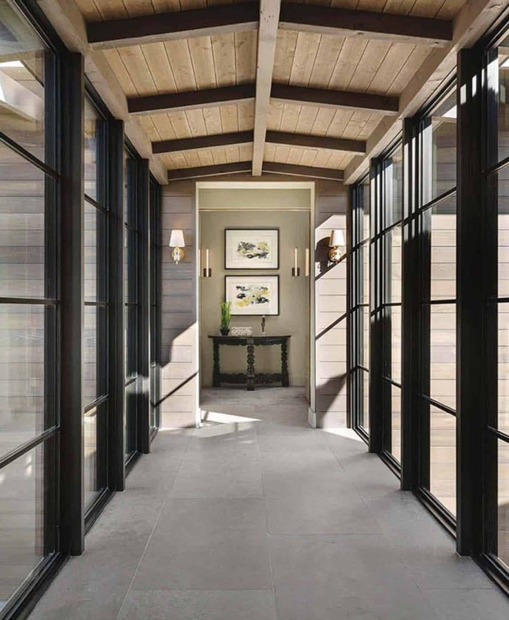 the hallway is lined with glass doors and wood paneled walls, along with an entry way that leads to another room