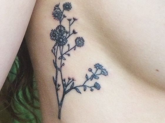 a close up of a flower tattoo on the side of a woman's stomach