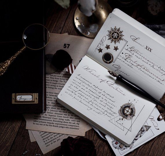 an open book with writing on it sitting next to other papers and accessories, including a pen