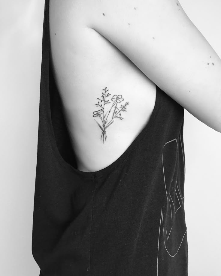 a black and white photo of a woman with a flower tattoo on her upper back