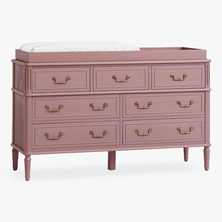 a pink dresser with gold handles and drawers