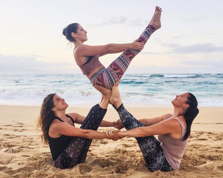 three women are doing yoga on the beach