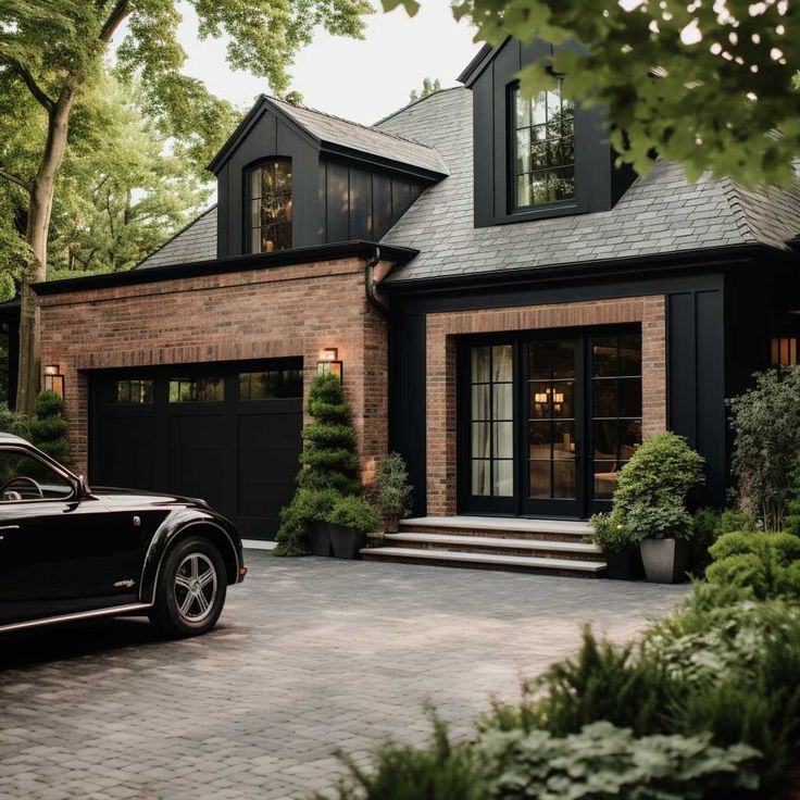 a black car is parked in front of a brick house with large windows and doors