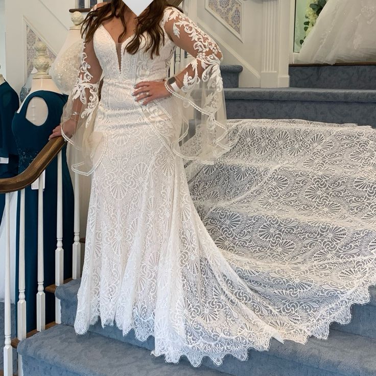 a woman in a white wedding dress standing on the stairs with her arms behind her back