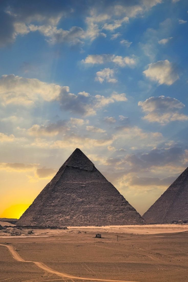 three pyramids in the desert under a cloudy sky