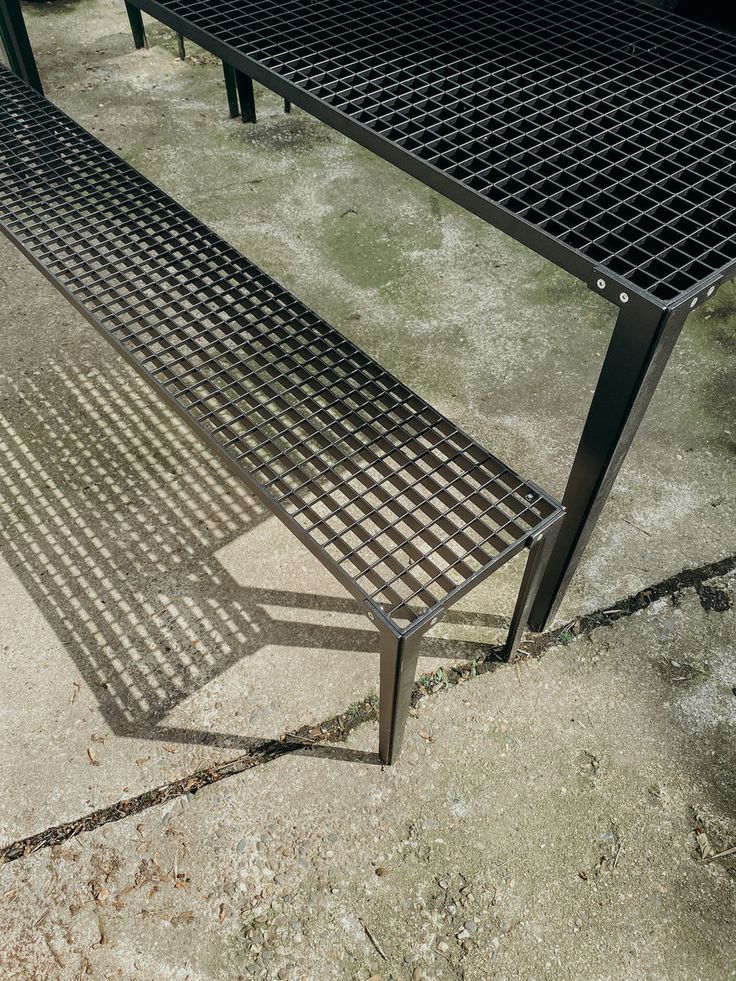 a metal bench sitting on top of a cement ground