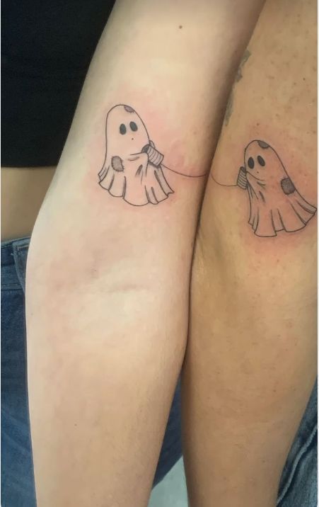 two people with tattoos on their legs that look like ghost hands and feet, one is holding the other's hand