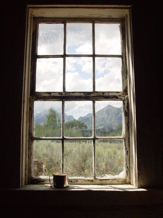 an open window with the view of mountains and grass in the distance, on a dark background