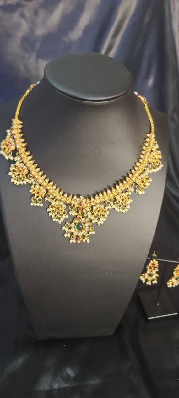 Traditional Pearl Necklace Set for Women will complement any Indian attire. Women Love Jewelry as it not only enhances their beauty, but also gives them the social confidence. Make your moment memorable with this jewel set that features a unique one of a kind traditional embellish. Dimension: 8 inch Yellow Gold Chandbali Kundan Temple Necklace, Kundan Temple Necklace With Latkans, Temple Jewelry 22k Gold Chandbali Kundan Necklace, 22k Gold Chandbali Kundan Necklace Temple Jewelry, 22k Gold Chandbali Kundan Temple Necklace, Kundan Temple Necklace With Zari Work, Chandbali-shaped Yellow Gold Bridal Necklace For Puja, Yellow Gold Chandbali Bridal Necklace For Puja, 22k Gold Chandbali Bridal Necklace With Pallu