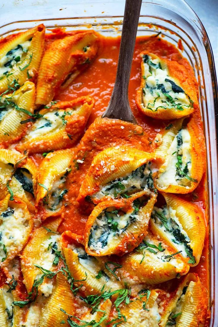 a casserole dish with pasta and spinach in tomato sauce, garnished with parsley