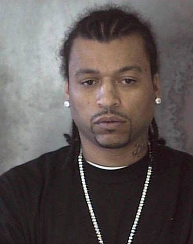 a man with dreadlocks wearing a black shirt and pearls on his necklace is looking at the camera